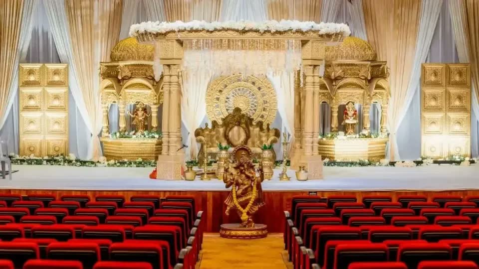 Gold mandap with Ganesha, carved gold panels and white florals